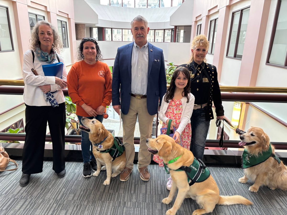 ECAD staff members and three service dogs in green ECAD vests standing with State Representative Bill Heffernan at the Connecticut State Capitol.